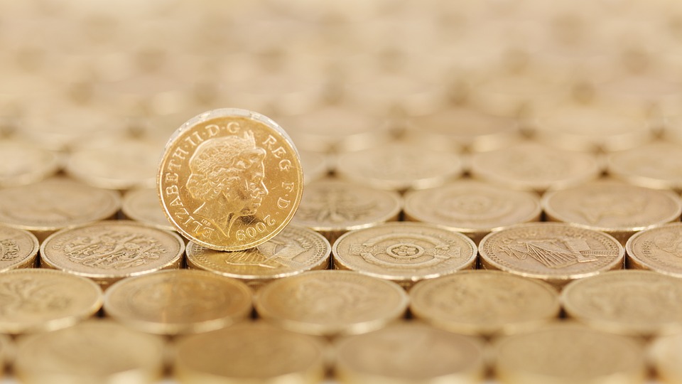 Pound coin standing on other pound coins which are laid out flat