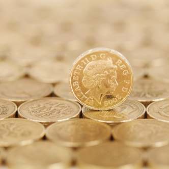 Pound coin standing on other pound coins which are laid out flat